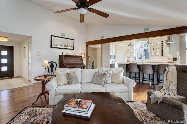 living room featuring ceiling fan, light hardwood / wood-style floors, and lofted ceiling