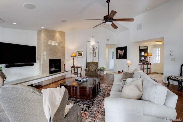 living room with a tile fireplace, hardwood / wood-style flooring, vaulted ceiling, and ceiling fan