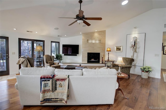 living room featuring wood-type flooring, a large fireplace, vaulted ceiling, and ceiling fan