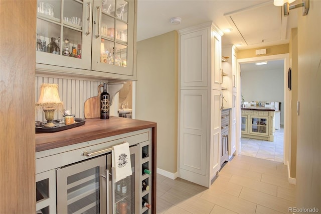 bar featuring white cabinets, beverage cooler, and wooden counters