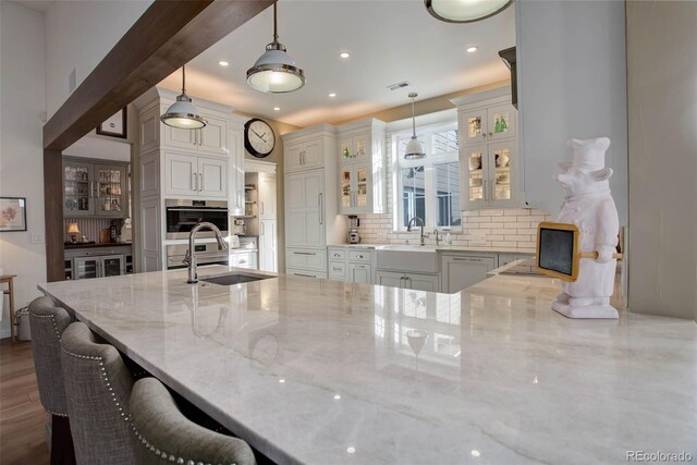 kitchen featuring decorative light fixtures, light stone countertops, and backsplash