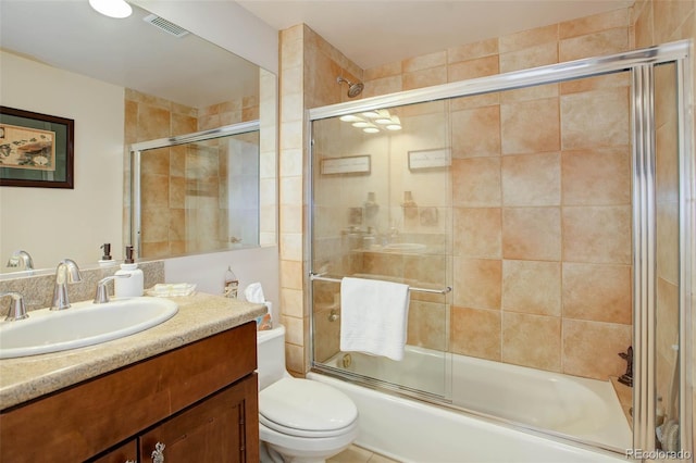 full bathroom with combined bath / shower with glass door, vanity, and toilet