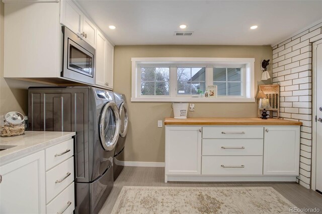 washroom featuring cabinets, separate washer and dryer, and light hardwood / wood-style flooring