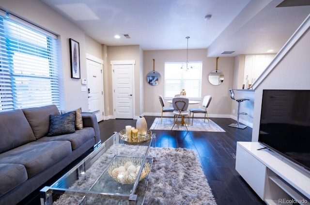 living room with a chandelier, a healthy amount of sunlight, and dark hardwood / wood-style flooring