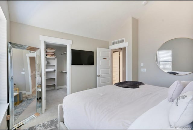 carpeted bedroom featuring a closet, vaulted ceiling, and a walk in closet