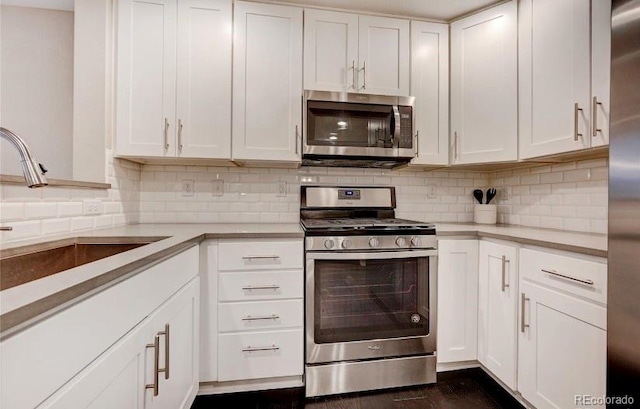 kitchen with white cabinets, tasteful backsplash, dark hardwood / wood-style floors, sink, and stainless steel appliances