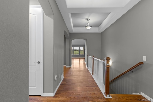 17223 W 84th Dr, Arvada, CO 80007 - corridor featuring arched walkways, a raised ceiling, wood finished floors, an upstairs landing, and baseboards