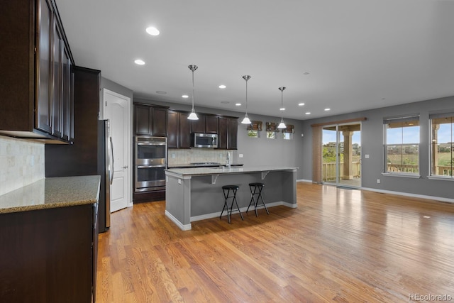 17223 W 84th Dr, Arvada, CO 80007 - kitchen with appliances with stainless steel finishes, recessed lighting, dark brown cabinets, tasteful backsplash, and a kitchen breakfast bar
