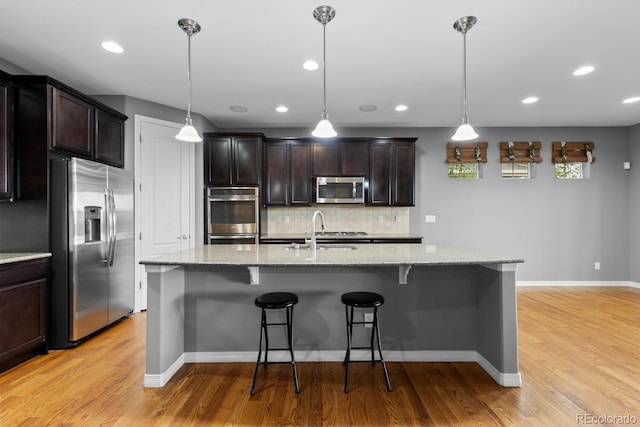 17223 W 84th Dr, Arvada, CO 80007 - kitchen featuring appliances with stainless steel finishes, a sink, light wood-style floors, tasteful backsplash, and light stone countertops