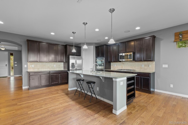 17223 W 84th Dr, Arvada, CO 80007 - kitchen with stainless steel appliances, dark brown cabinetry, arched walkways, tasteful backsplash, and recessed lighting