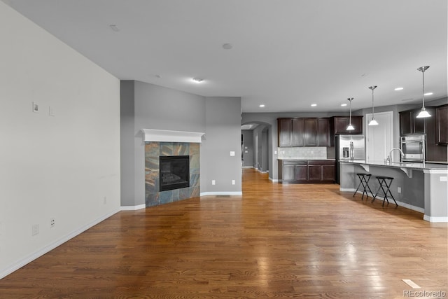 17223 W 84th Dr, Arvada, CO 80007 - unfurnished living room featuring recessed lighting, wood finished floors, baseboards, a sink, and arched walkways