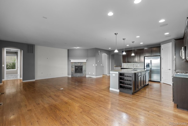 17223 W 84th Dr, Arvada, CO 80007 - kitchen featuring stainless steel refrigerator with ice dispenser, arched walkways, a sink, dark brown cabinets, and a tiled fireplace