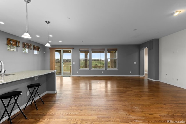 17223 W 84th Dr, Arvada, CO 80007 - kitchen with arched walkways, light wood finished floors, a sink, recessed lighting, and baseboards