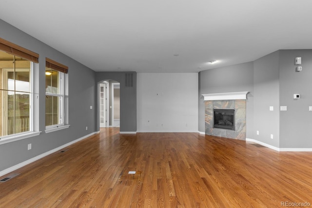 17223 W 84th Dr, Arvada, CO 80007 - unfurnished living room with wood finished floors, arched walkways, a fireplace, and baseboards