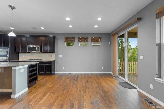 17223 W 84th Dr, Arvada, CO 80007 - kitchen with stainless steel appliances, decorative backsplash, light stone countertops, wood finished floors, and recessed lighting