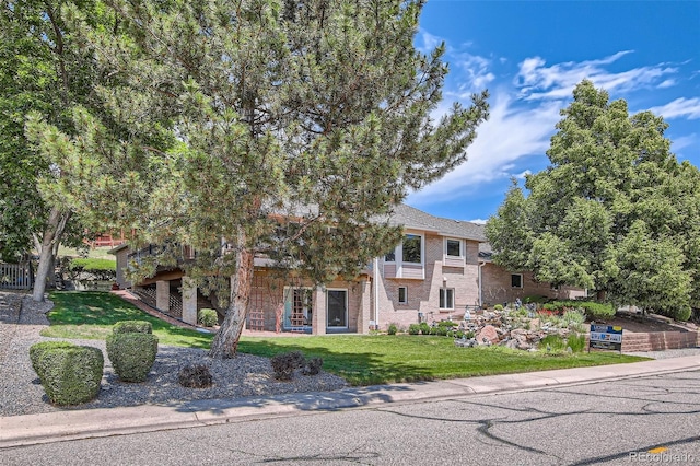 7769 W 70th Dr, Arvada, CO 80004 - view of property hidden behind natural elements featuring a front lawn and brick siding