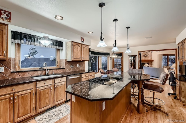 7769 W 70th Dr, Arvada, CO 80004 - kitchen with dishwasher, black electric stovetop, light wood finished floors, a kitchen bar, and a center island