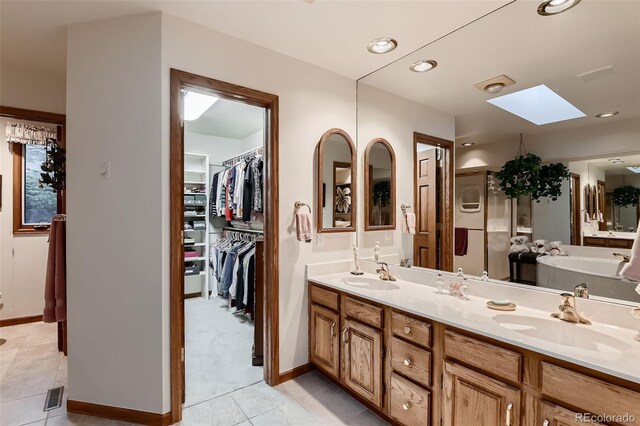 7769 W 70th Dr, Arvada, CO 80004 - full bathroom with a skylight, double vanity, tile patterned flooring, a garden tub, and a walk in closet