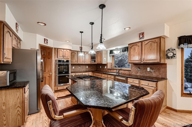 7769 W 70th Dr, Arvada, CO 80004 - kitchen featuring appliances with stainless steel finishes, light wood finished floors, a breakfast bar area, backsplash, and recessed lighting