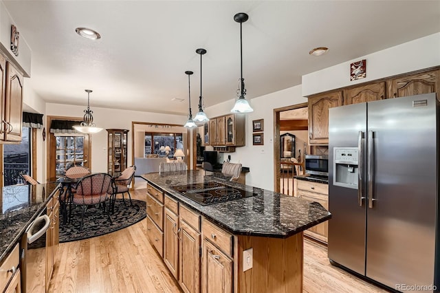 7769 W 70th Dr, Arvada, CO 80004 - kitchen featuring stainless steel appliances, light wood-type flooring, a center island, pendant lighting, and dark stone countertops