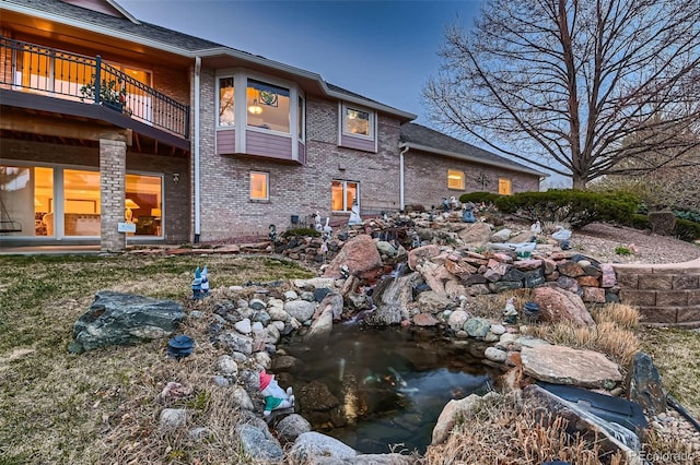 7769 W 70th Dr, Arvada, CO 80004 - back of property featuring a balcony, brick siding, and a garden pond