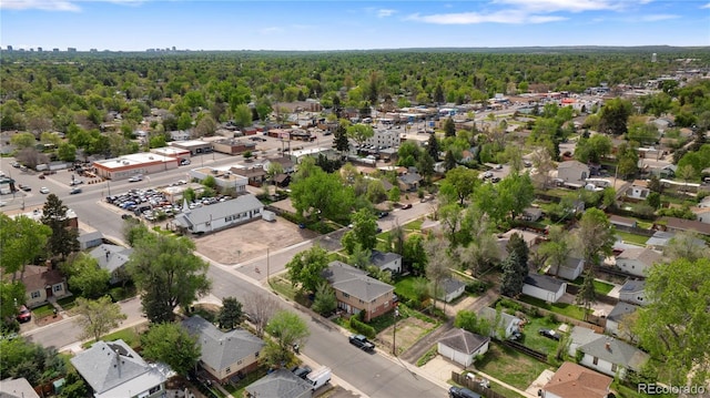 aerial view of property and surrounding area with a forest and nearby suburban area