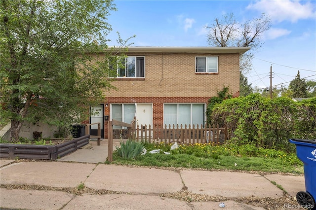multi unit property featuring a fenced front yard and brick siding