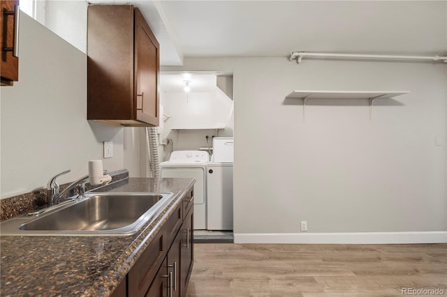 clothes washing area featuring washing machine and clothes dryer, light wood-type flooring, and baseboards