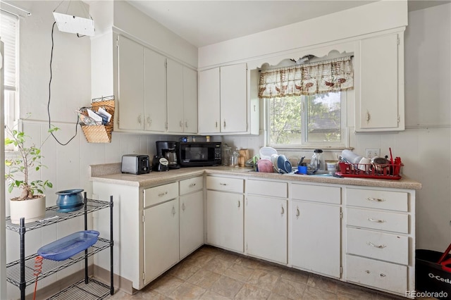 kitchen featuring black microwave, light countertops, and white cabinetry
