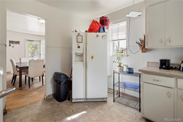 kitchen featuring white fridge with ice dispenser, light countertops, and hanging light fixtures