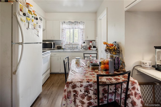 kitchen with freestanding refrigerator, stainless steel microwave, a sink, range, and wood finished floors