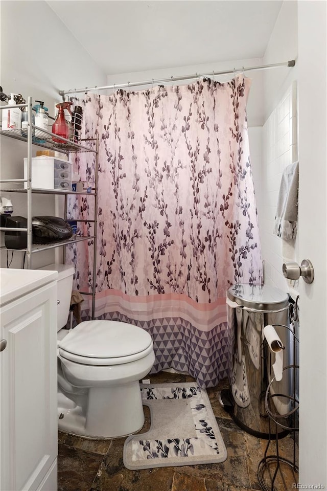full bathroom featuring stone tile flooring, toilet, a shower with shower curtain, and vanity