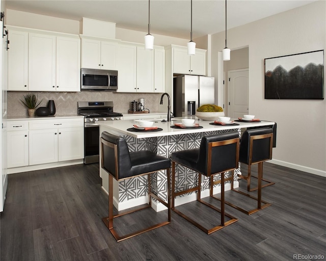 kitchen with decorative light fixtures, an island with sink, white cabinetry, a kitchen breakfast bar, and stainless steel appliances