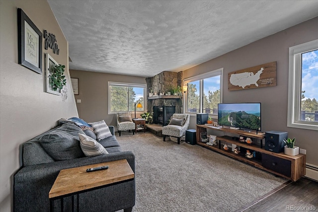 living room featuring a healthy amount of sunlight, a stone fireplace, and a textured ceiling