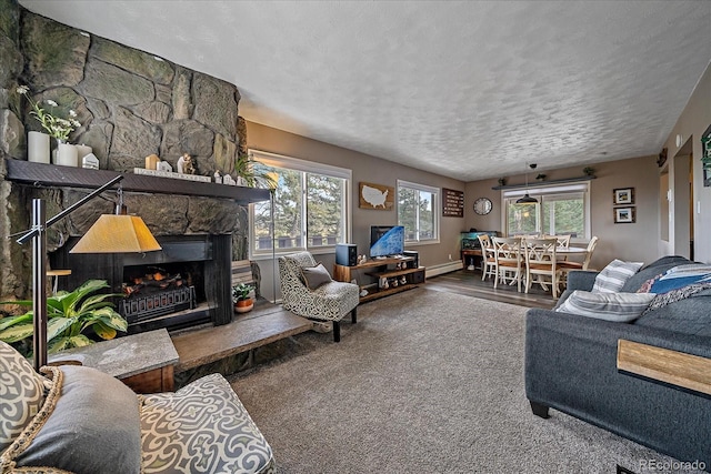 living room with hardwood / wood-style floors, a baseboard radiator, a stone fireplace, and a textured ceiling