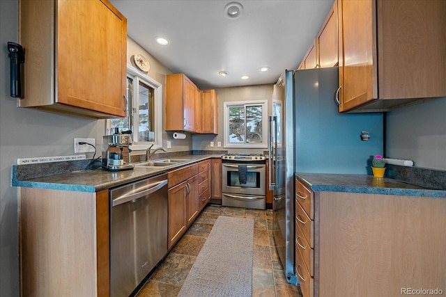 kitchen with appliances with stainless steel finishes, sink, and dark tile floors