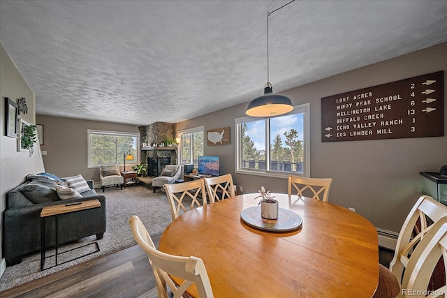 dining area with hardwood / wood-style flooring, a textured ceiling, and a fireplace