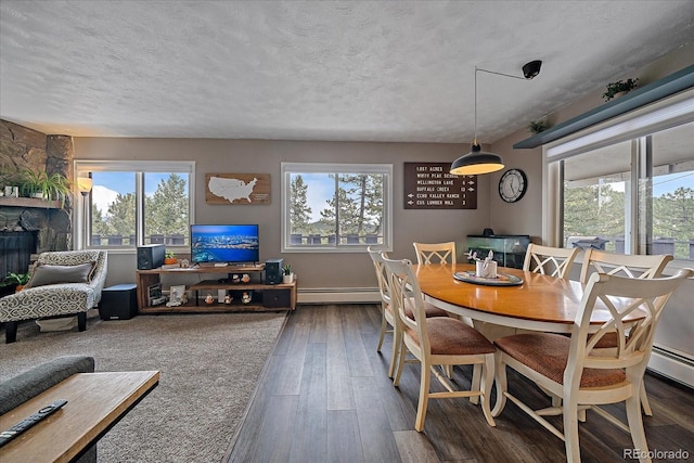 dining room featuring plenty of natural light, a baseboard heating unit, and a textured ceiling