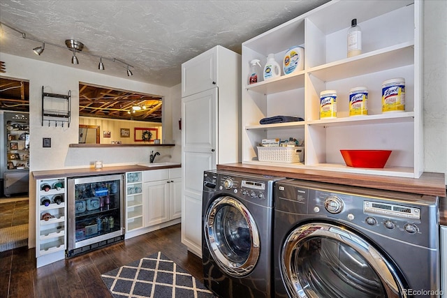 laundry room featuring cabinets, washing machine and clothes dryer, wine cooler, sink, and dark hardwood / wood-style flooring