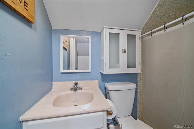 bathroom with lofted ceiling, toilet, and vanity with extensive cabinet space