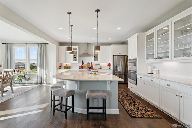 3741 Harvard Pl, Broomfield, CO 80023 - kitchen with appliances with stainless steel finishes, wall chimney exhaust hood, white cabinets, a kitchen island, and a kitchen breakfast bar