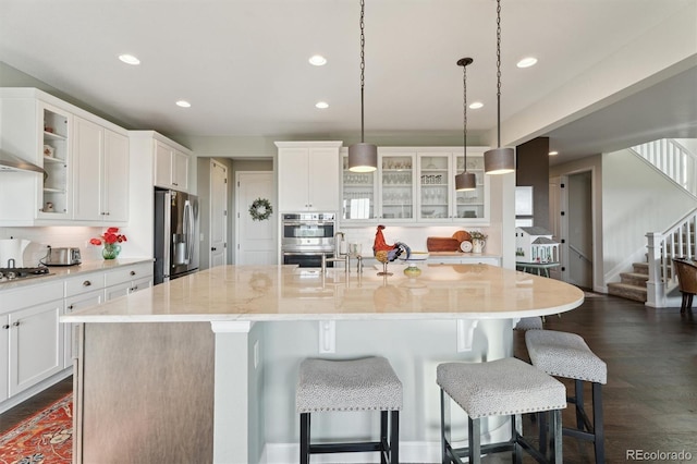 3741 Harvard Pl, Broomfield, CO 80023 - kitchen with appliances with stainless steel finishes, an island with sink, a kitchen bar, decorative backsplash, and white cabinetry