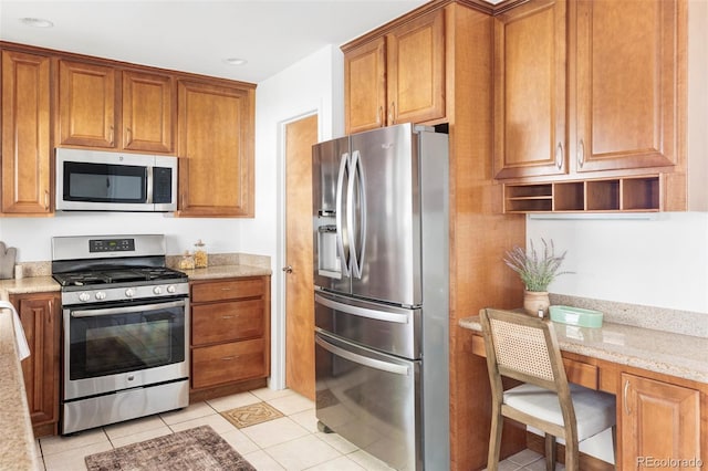 6580 Independence Way, Arvada, CO 80004 - kitchen featuring appliances with stainless steel finishes, light tile patterned floors, brown cabinets, light stone countertops, and recessed lighting
