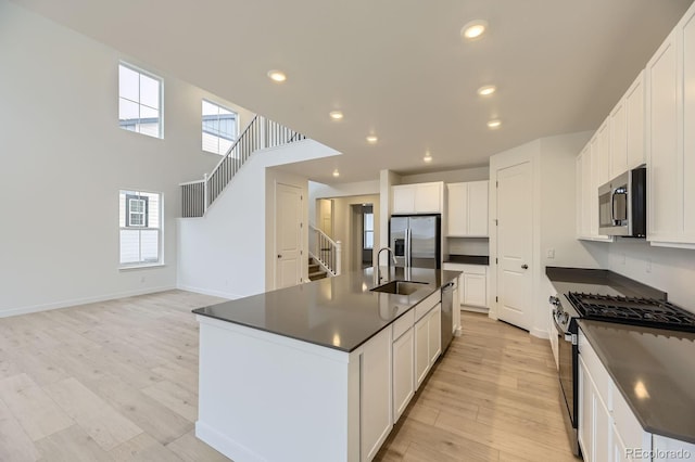 39857 Floyd St, Elizabeth, CO 80107 - kitchen with appliances with stainless steel finishes, dark countertops, recessed lighting, light wood-style flooring, and a kitchen island with sink