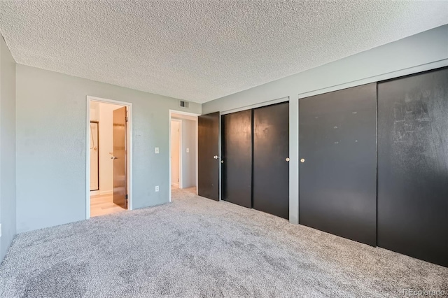 unfurnished bedroom featuring two closets, carpet flooring, and a textured ceiling