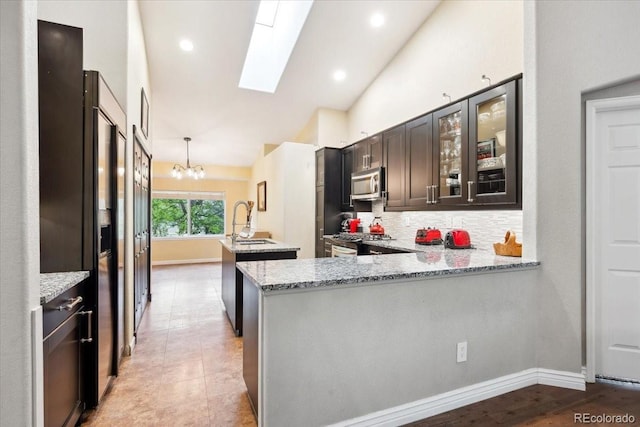 19113 W 60th Ln, Golden, CO 80403 - kitchen featuring stainless steel appliances, a center island with sink, a skylight, a chandelier, and light stone countertops