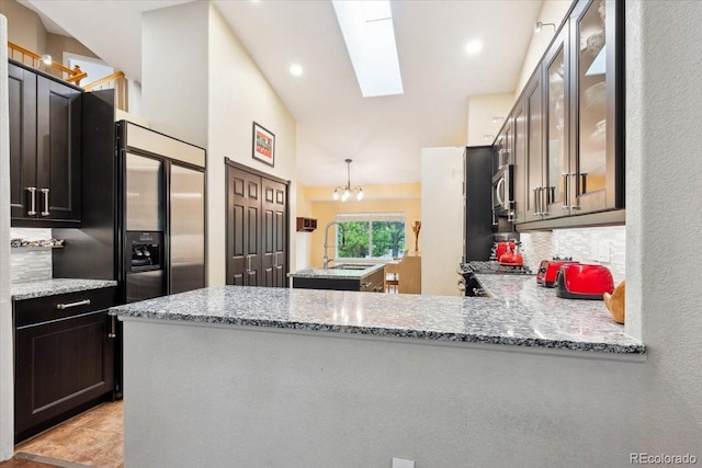 19113 W 60th Ln, Golden, CO 80403 - kitchen featuring light stone counters, stainless steel appliances, a skylight, glass insert cabinets, and a chandelier
