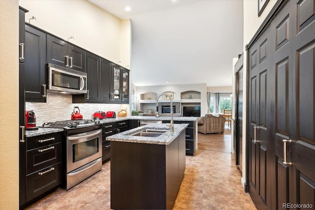 19113 W 60th Ln, Golden, CO 80403 - kitchen with appliances with stainless steel finishes, an island with sink, light stone countertops, open floor plan, and a towering ceiling