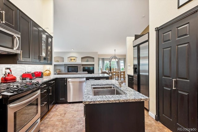 19113 W 60th Ln, Golden, CO 80403 - kitchen with stainless steel appliances, a peninsula, light stone counters, a center island with sink, and glass insert cabinets