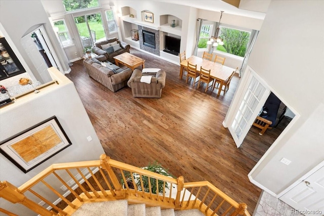 19113 W 60th Ln, Golden, CO 80403 - living area featuring a fireplace, healthy amount of natural light, wood finished floors, built in shelves, and a high ceiling